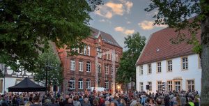 Das Foto zeigt den Klosterplatz und einen Ausschnitt aus einer Performance des Bielefelder Sommertheaters.